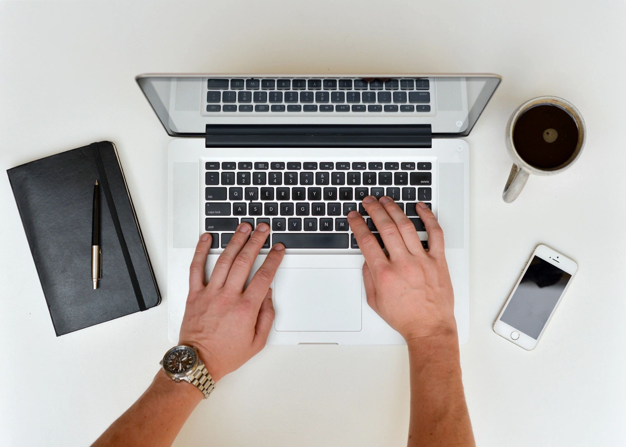 Professional workspace with a laptop, notebook, coffee and phone